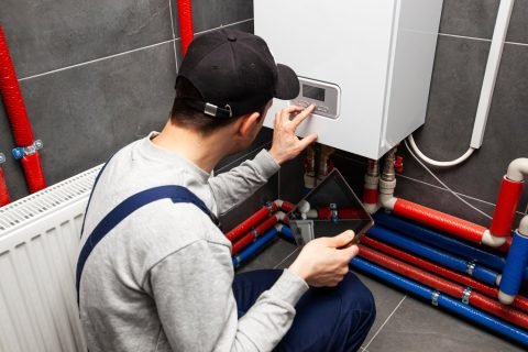 The-technician-checking-the-heating-system-in-the-boiler-room-with-tablet-in-hand The-technician-checking-the-heating-system-in-the-boiler-room-with-tablet-in-hand