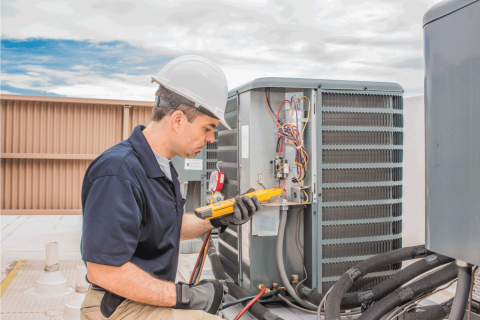 Trained-hvac-technician-holding-a-voltage-meter-performing-preventative-maintenance-on-a-air-conditioning-condenser-unit
