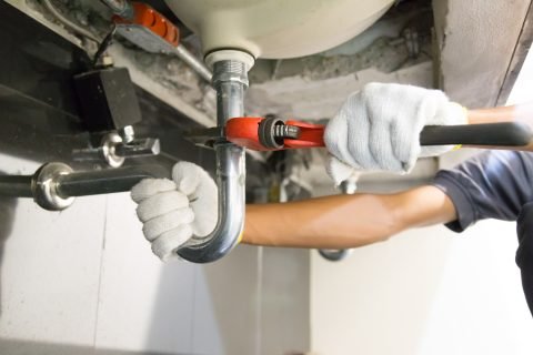 Plumber fixing white sink pipe with adjustable wrench. Residential Plumbing Service in Augusta, GA