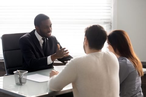 couple-discuss-with-man-at-desk-getty